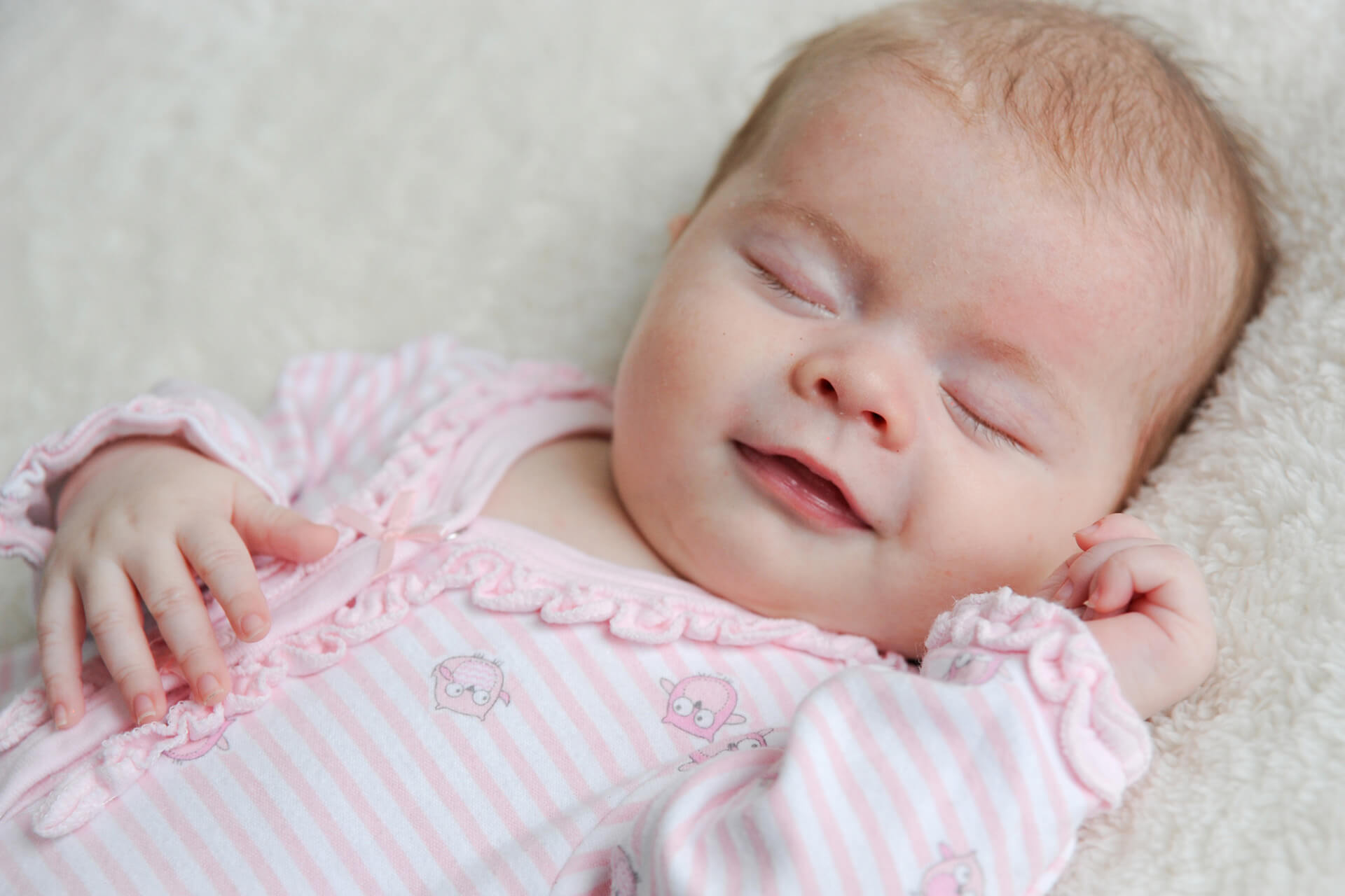 Best Detroit baby photographer covers all the bases of classic infant portraits and lifestyle candid baby photography in metro Detroit, Michigan like this baby's fleeting smile during an infant baby session.