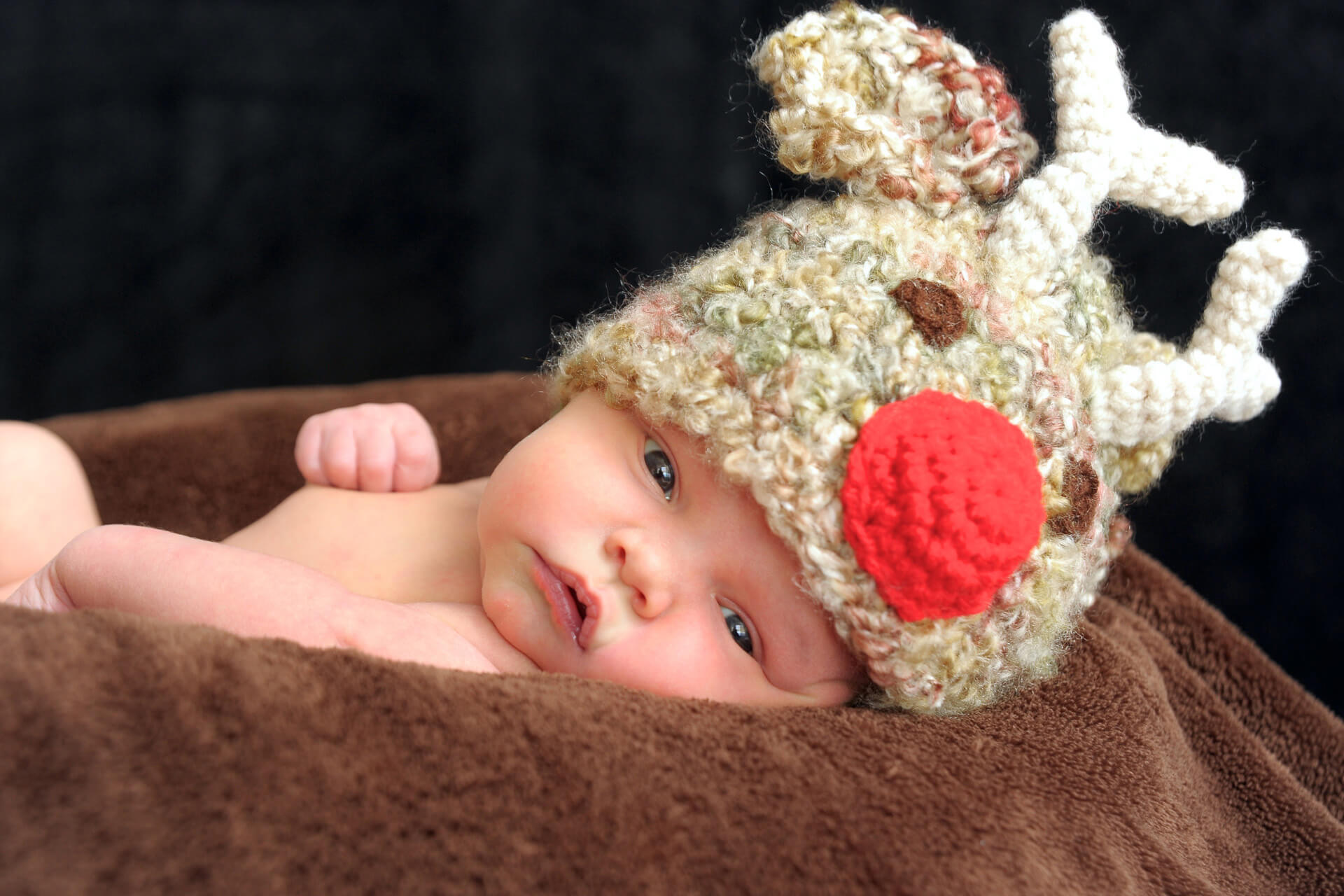 Best Detroit baby photographer photographs families bring fun baby hats from Etsy for their for newborn photos in Troy, Michigan.