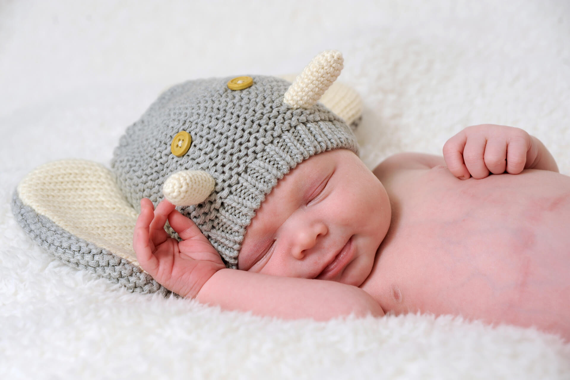 Best Detroit infant photographer capturing fun baby poses like this sleeping, smiling baby in my studio in Troy, the metro Detroit, Michigan area.