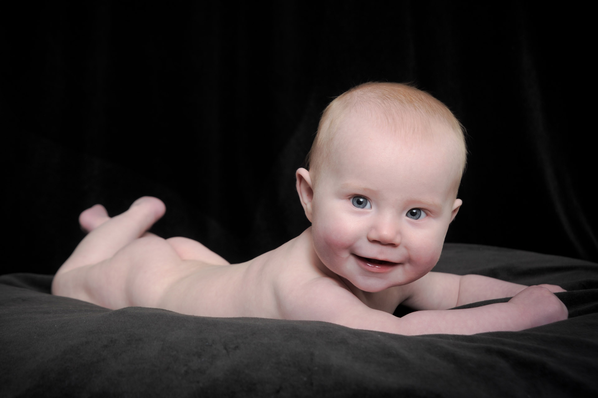 Best Detroit infant photographer's fun and candid baby photos of a Detroit newborn seemingly posing for his 6 month old baby photo in metro Detroit, Michigan.