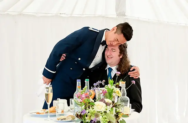 Military member hugs the groom during dinner as a welcome to the family gesture during a destination wedding in Edinburgh, Scotland