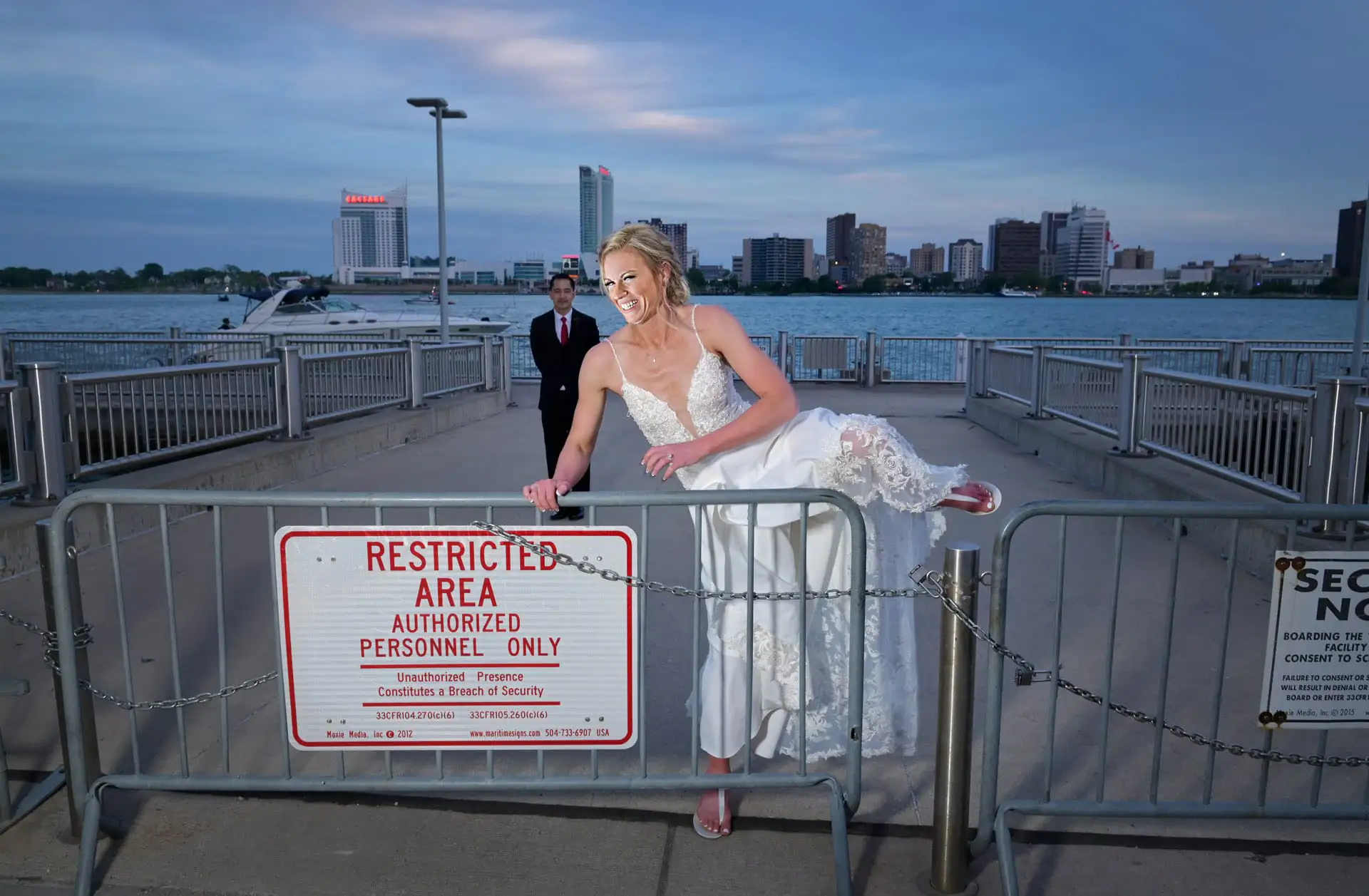 A slightly older bride heads over a barricade in front of their Waterview Loft wedding venue downtown Detroit, Michigan.
